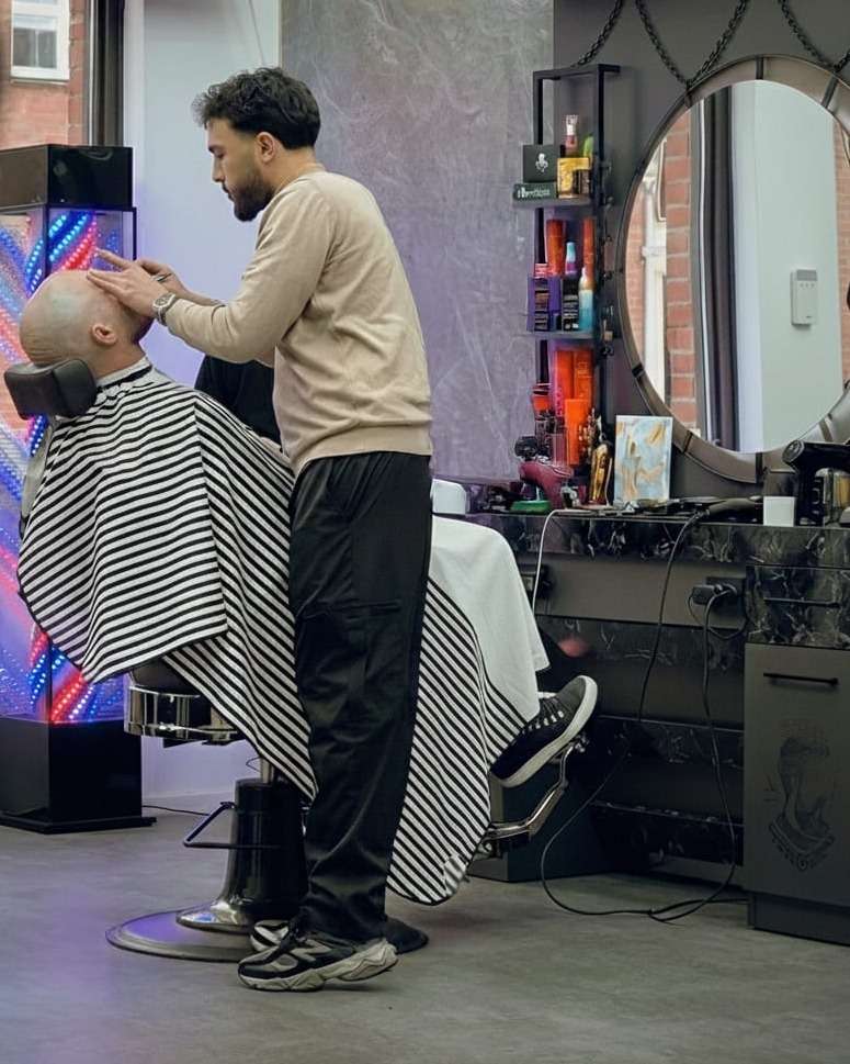 Barber scheert het hoofd van een klant glad bij City Style Barbershop aan de Promenade 23