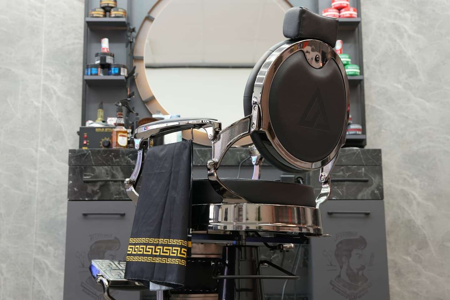 Zwarte barberstoel met kapmantel voor een spiegel bij City Style Barbershop